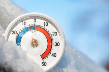 Thermometer with celsius scale in the snow showing minus 5 degree ambient temperature - winter weather concept