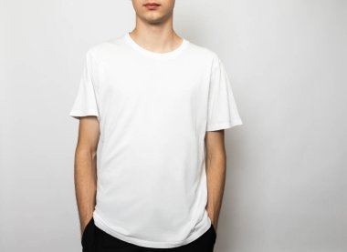 Relaxed young man wearing blank white cotton T-Shirt. Studio shot on gray background
