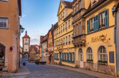 Rothenburg ob der Tauber, Almanya - 10 Mayıs 2019: Schmiedgasse caddesi boyunca Plonlein (Little Square) ve Siebers Tower 'ın arka planda görüldüğü oteller ve dükkanlar
