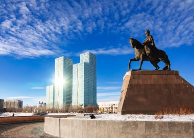 Astana, Kazakistan - 25 Ocak 2023: Ishim Nehri setindeki Kenesary Khan anıtı. Güneş, arka planda görülen modern Grand Alatau konut kompleksinin camsı cephesini yansıtır.