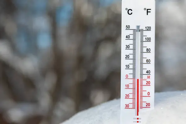 雪に置かれた摂氏温度と華氏スケールの屋外温度計のクローズアップショットは凍結点温度を表示します ストック写真