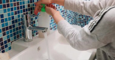 Çocuk ellerini sabun ve suyla özenle yıkıyor Coronavirus COVID-19 hastalığının yayılmasına karşı temel koruma önlemlerini uyguluyor.