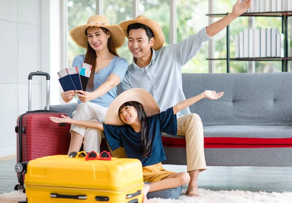 Millennial Asian happy family father mother and little girl daughter wearing casual summer travel outfit preparing packing stuff in trolley luggage ready to vacation holiday in living room at home.