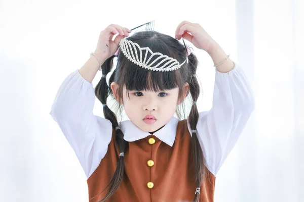 千年紀の閉鎖ショットアジアの幸せな陽気少しかわいいです就学前の娘の女の子の役割一人立ち身に着けているダイヤモンドプリンセスクラウンTiaraヘッドバンド上の頭の上にライトカーテン背景 — ストック写真