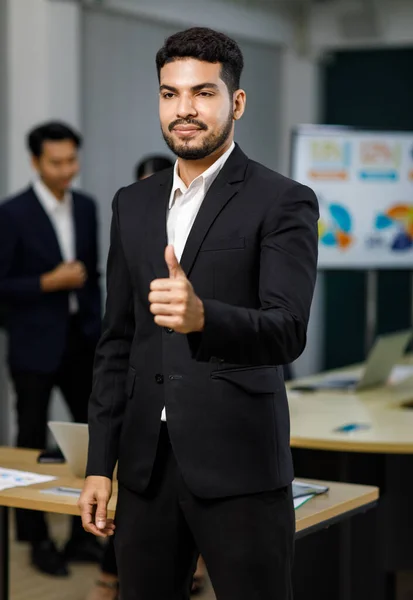 Millennial Asian Indian professional successful bearded male businessman entrepreneur ceo management in formal business suit standing smiling posing in company office meeting room