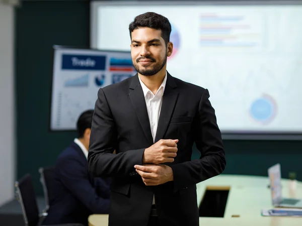 Millennial Asian Indian professional successful bearded male businessman entrepreneur ceo management in formal business suit standing smiling crossed arms portrait photo in company office meeting room