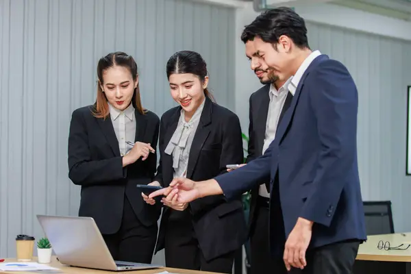 Millennial Asian Indian professional male businessmen female businesswomen employee staff colleagues in formal business suit standing discussing brainstorming working together with laptop computer.