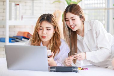 İki mutlu Asyalı güzel bayan kozmetik, cilt güzellik ürünlerine yüz bakımı yapar, dizüstü bilgisayar seyreden kadın, beyaz bir yatakta dinlenir, ergen ya da evdeki arkadaş yaşam tarzını kavrar..