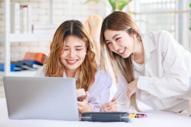 İki mutlu Asyalı güzel bayan kozmetik, cilt güzellik ürünlerine yüz bakımı yapar, dizüstü bilgisayar seyreden kadın, beyaz bir yatakta dinlenir, ergen ya da evdeki arkadaş yaşam tarzını kavrar..