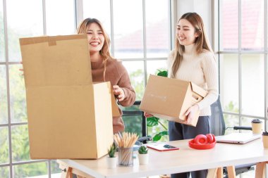 İki ev arkadaşı mutlu Asyalı genç bayan eşyalarını yeni bir daireye taşıyor, karton kutular taşıyor, genç ya da arkadaşları kavramsallaştırıyor, gayrimenkul satın alıyor, taşınıyor, yeni bir eve taşınıyor.