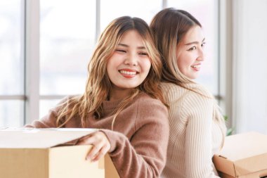 İki ev arkadaşı mutlu Asyalı genç bayan eşyalarını yeni bir daireye taşıyor, karton kutular taşıyor, genç ya da arkadaşları kavramsallaştırıyor, gayrimenkul satın alıyor, taşınıyor, yeni bir eve taşınıyor.