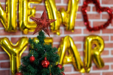 Kırmızı yıldızlı Noel ağacını kapat ve balonlu tuğla duvarın arkasında mutlu bir yeni yıl ve tatil konsepti için fotokopi alanı..