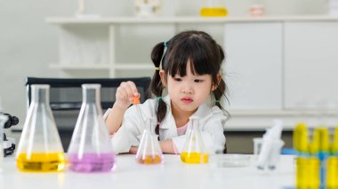 Laboratuvar önlüğü giymiş Asyalı küçük şirin kız öğrenciler deney tüpü bilim deneyleri yapıyorlar. Okulda kimya laboratuvarında. Eğitim araştırma ve geliştirme kavramı çocukları eğitiyor.