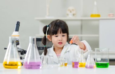 Laboratuvar önlüğü giymiş Asyalı küçük şirin kız öğrenciler deney tüpü bilim deneyleri yapıyorlar. Okulda kimya laboratuvarında. Eğitim araştırma ve geliştirme kavramı çocukları eğitiyor.