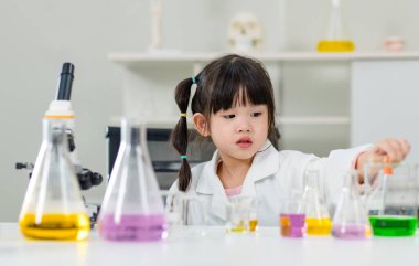 Laboratuvar önlüğü giymiş Asyalı küçük şirin kız öğrenciler deney tüpü bilim deneyleri yapıyorlar. Okulda kimya laboratuvarında. Eğitim araştırma ve geliştirme kavramı çocukları eğitiyor.