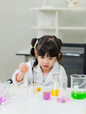 Laboratuvar önlüğü giymiş Asyalı küçük şirin kız öğrenciler deney tüpü bilim deneyleri yapıyorlar. Okulda kimya laboratuvarında. Eğitim araştırma ve geliştirme kavramı çocukları eğitiyor.