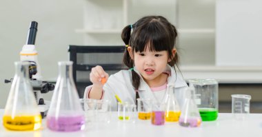 Laboratuvar önlüğü giymiş Asyalı küçük şirin kız öğrenciler deney tüpü bilim deneyleri yapıyorlar. Okulda kimya laboratuvarında. Eğitim araştırma ve geliştirme kavramı çocukları eğitiyor.