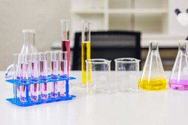 Cam test tüpleri, masanda çeşitli renkli sıvılar bulunan deney tüpleri, korumak için aşı yapmak için çalışma, laboratuvar içi arka plan. Kimyasal laboratuvar araştırma ve geliştirme bilim konsepti.