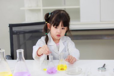 Laboratuvar önlüğü giymiş Asyalı küçük şirin kız öğrenciler deney tüpü bilim deneyleri yapıyorlar. Okulda kimya laboratuvarında. Eğitim araştırma ve geliştirme kavramı çocukları eğitiyor.
