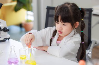 Laboratuvar önlüğü giymiş Asyalı küçük şirin kız öğrenciler deney tüpü bilim deneyleri yapıyorlar. Okulda kimya laboratuvarında. Eğitim araştırma ve geliştirme kavramı çocukları eğitiyor.