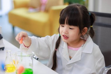 Laboratuvar önlüklü Asyalı küçük şirin kız öğrenciler, deney tüpü bilimi deneyleri yapmayı düşünüyorlar. Okulda kimya laboratuvarında. Eğitim araştırma ve geliştirme kavramı çocukları eğitiyor.