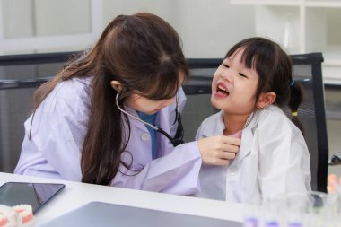 Asyalı kadın doktor ve neşeli küçük kız laboratuardaki doktor randevularına steteskop uyguluyorlar. Eğitim sağlık hizmetleri, tıp çocuklar için hastane konsepti çocuklar için öğrenme