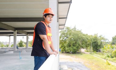 Asyalı inşaat şantiyesi yöneticisi inşaat mühendisi ustabaşı güvenlik donanımı ve miğfer taşıyan ustabaşı inşaat şantiyesi mimarı için tablet planlama projesi çalışması yapıyor..