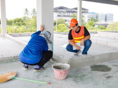 Asyalı inşaat mühendisi, güvenlik önlüğü takıyor, çelik yelek giyiyor, görüş mesafesi yüksek, işçilerin inşaat alanında veya inşaat geliştirme konseptinde çalışmalarını denetliyor..