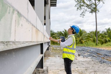 Asyalı inşaat mühendisi inşaat mühendisi ustabaşı güvenlik donanımı ve miğfer taşıyan miğfer taşıma tablet planlama projesi ve mimar geliştirme çalışmalarını denetliyor.