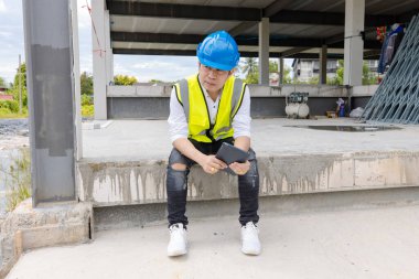 Asyalı inşaat alanı yöneticisi inşaat mühendisi ustabaşı güvenlik donanımı ve kask oturma planı üzerinde inşaat alanı mimari konsepti için proje çalışması.