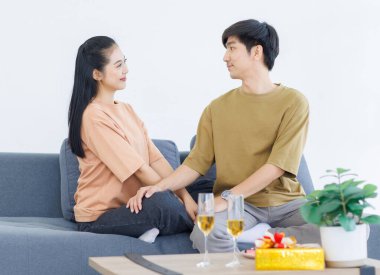 Asyalı, genç, mutlu, çekici bir çift. Sevgililer gülümser. Sarılırlar, evdeki rahat koltukta otururlar..