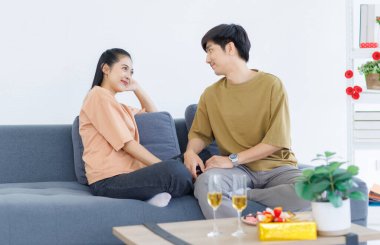 Asyalı, genç, mutlu, çekici bir çift. Sevgililer gülümser. Sarılırlar, evdeki rahat koltukta otururlar..