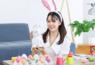 Asyalı, çekici, neşeli, sevimli, tatlı bir kadın. Günlük kıyafetler giyiyor. Tavşan kulakları takıyor. Mutlu bir gülümseme.