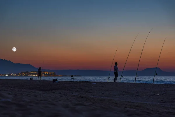 Люди Рыбу Пляже Несколькими Стержнями Сумерках Полная Суперлуна Видна Над — стоковое фото