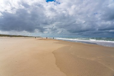 Yürüyüşçüler ve balıkçılar Vlieland sahilinin üzerindeki güzel bulutların tadını çıkarıyorlar.