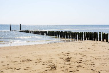 Güneş, Zeeland, Zoutelande 'deki kazık tepelerinde gelgit sırasında denizde parlıyor.