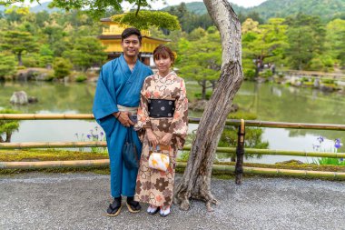 Japon bir gelin çifti balayında Kyoto, Japonya 'daki altın Kinkakuji tapınağının önünde poz veriyor..
