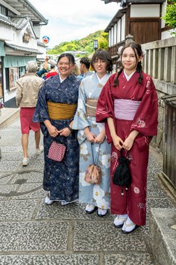 Japonya, Kyoto 'daki Yasaka Pagoda' nın yakınlarındaki bir alışveriş sokağında geleneksel giysiler içinde üç genç bayan.