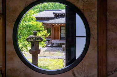 Japonya 'daki Nikko Tammozawa İmparatorluk Konağı' nın yuvarlak penceresinden geleneksel bir binanın atmosferik manzarası.