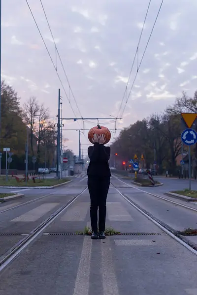 stock image Halloween. Pumpkinhead. A man with a pumpkin on his head on the streets of the morning city.