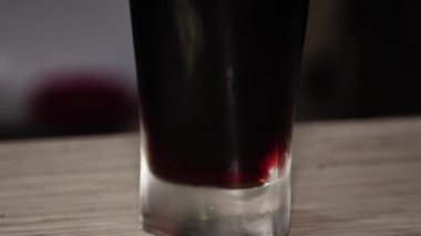 Yakın plan, pürüzsüz kamera hareketi, tezgahın arkasında bir bardak köpüklü koyu bira..