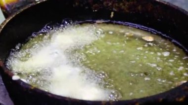 Aşçının ellerine yakın çekim yap ve hamuru kızartma tavasındaki kızgın yağın içine koy..