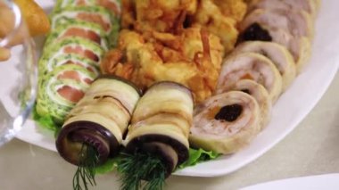 Seçici odak, düzgün kamera hareketi, dilimlenmiş abur cuburların yakın çekimi, et ve sebze ruloları bir tabakta..