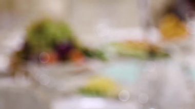 Pürüzsüz kamera hareketi, Bokeh 'ten salata ve aperatiflerle dolu bir masaya seçici bir odak noktası..