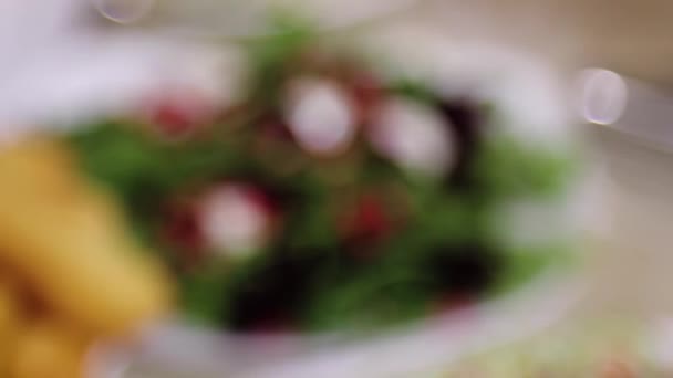 滑らかなカメラの動き レストランでサラダや前菜とテーブルにボケから選択的な焦点 — ストック動画
