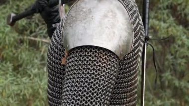 Ortaçağ savaşçısı portresi, gri saçlı, yüzünde zincirli bir yara izi, omuzlarında vatkalarla ormanın zeminine karşı duran iki elli bir kılıç. Orta Çağ Cadısı