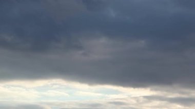 Karanlık, kasvetli bulutlarla, gün batımının erken saatlerinde gökyüzünde pürüzsüz kamera hareketleri.