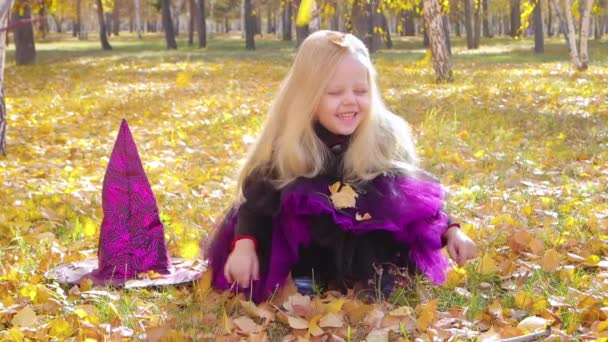 Little Girl Witch Costume Sits Grass Park Catches Falling Yellow — Wideo stockowe
