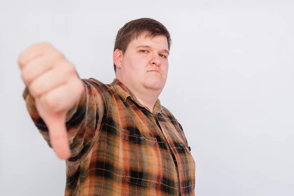 Fat guy showing thumbs down isolated on white background. Young man making a gesture, I don\'t like it, bad job. Body language, body positivity.