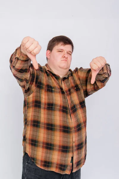 Fat guy showing thumbs down isolated on white background. Young man making a gesture, I don\'t like it, bad job. Body language, body positivity.